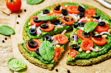 vegan broccoli zucchini pizza crust with spinach pesto, tomatoes, onion and olives