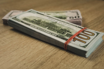 a bundle of american dollars tied with a rubber band on a wooden background.