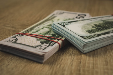 a bundle of american dollars tied with a rubber band on a wooden background.