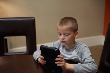 Boy using tablet indoors to learn. 