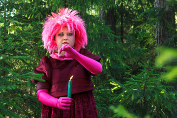 Forest witch in purple clothes conjures among the forest with candles. Vertical photo