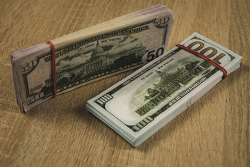a bundle of american dollars tied with a rubber band on a wooden background.