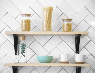 Fototapeta na wymiar Wooden kitchen shelves with cups and glass Jars