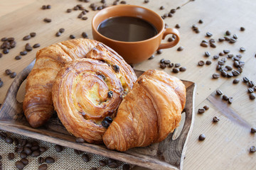 Sweet breakfast: black coffee, croissants and a roll with raisins