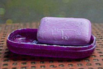 wet piece of lilac soap in a plastic box on a brown table