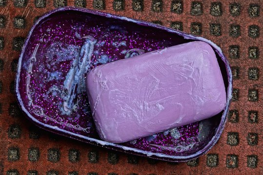 piece of lilac soap in a plastic box on a brown table