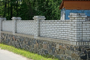 a long private fence of white bricks and gray stones