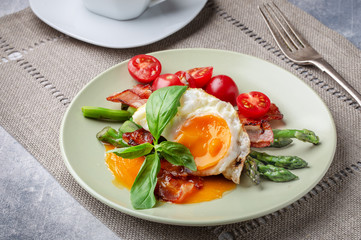 Fried egg with crispy bacon and asparagus on plate for breakfast 