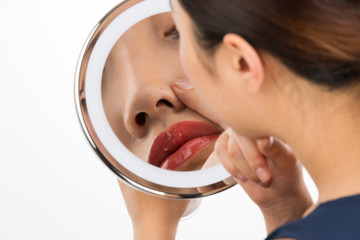 鏡で鼻を見る女性