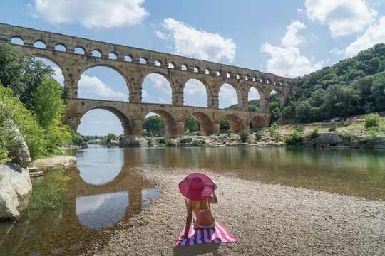 Woman wearing pink hat sunbathing by Pont du Gard in Vers-Pont-du-Gard, France