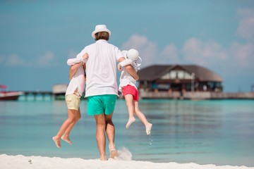 Happy father and his adorable little daughters at tropical beach having fun