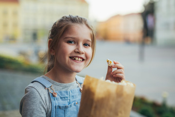 positive little girl eating popcorn outdoor