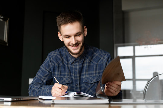 Smiling young businessman writing in note pad