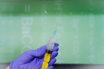 Hands in rubber gloves hold a disposable medical syringe with the drug