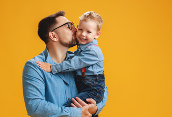 happy father's day! cute dad and son hugging on yellow background