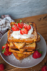 French toast with fresh strawberries, coconut shreds and honey, on wooden background