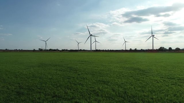 Green Energy, gliding aerial shot of windfarm in horizon