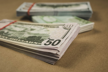 several wads of cash lying on top of each other on a beige background.