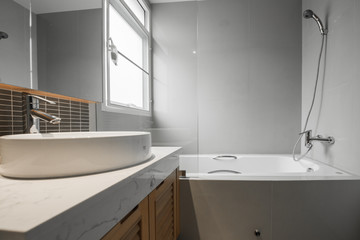 Condo bathroom design with single vanity cabinet and grey tiles on the walls.
