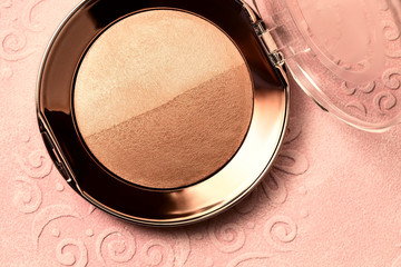 Powder on a pink background, macro image of cosmetics, two-tone bronzer and highlighter