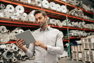 Warehouse manager using a digital tablet while tracing stock