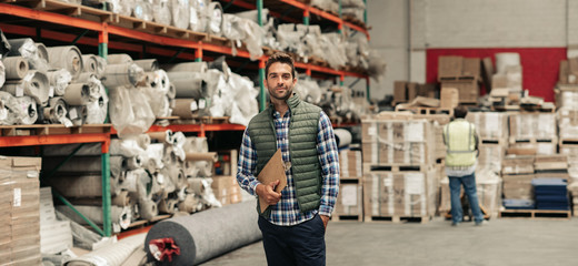 Worker standing with an inventory clipboard on a warehouse floor