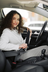 Fototapeta na wymiar Closeup portrait of young woman fasten seat belt in her car
