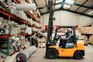 Forklift driver carefully moving stock around a large warehouse © mavoimages