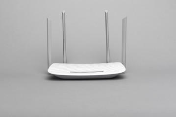 White modern Wi-Fi router with four antennas on a gray background. - obrazy, fototapety, plakaty