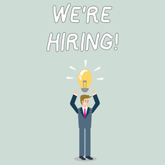 Word writing text We Re Hiring. Business photo showcasing recently employ someone or pay someone to do particular job Businessman Standing Raising Arms Upward with Lighted Bulb Icon on his Head