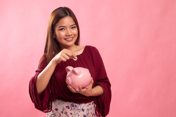 Asian woman with coin and pig coin bank.