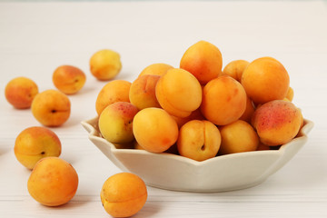Ripe apricots are located on a plate on a white background