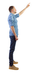 Side view of a man in jeans points his hand upwards.