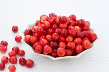 Berries of a sweet cherry are located in a plate on a white background