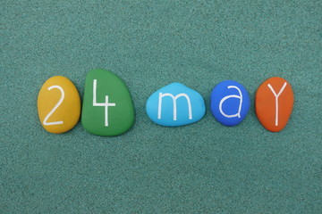 24 May, calendar date composed with multi colored stones over green sand