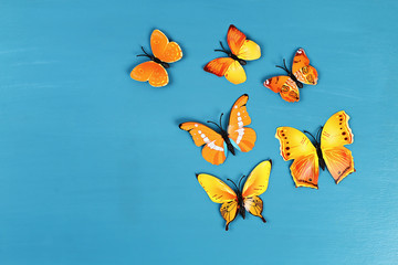 Fototapeta premium Yellow and orange butterflies on blue background. Top view. Summer background. Flat lay.