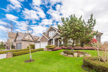 Beautiful exterior of newly built luxury home. Yard with green grass and stone.