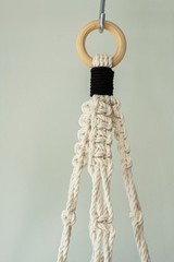 A hand-made macrame plant hanger made using 100% natural cotton. This is the top of the macrame. The wooden ring is shown.