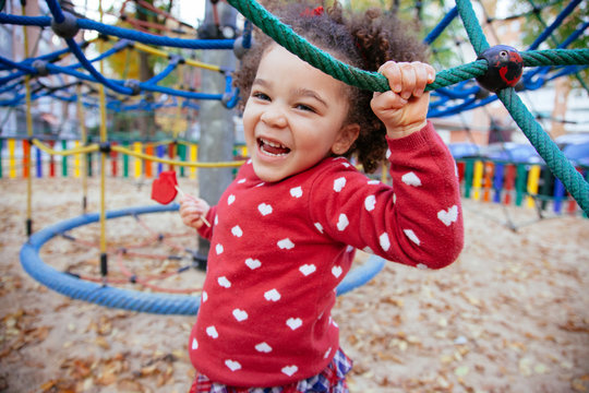 healthy african american little girl having a fun time. Crazy small kid bouncing back and forward in the playground outdoors