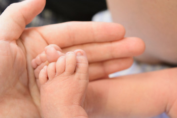 Small cute newborn baby's feet with man's hand