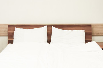 Two white pillows in bed. Minimalism in hotel. Wooden bed