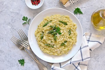 Italian risotto with spring asparagus and parmesan cheese on light background. Top view with copy space.