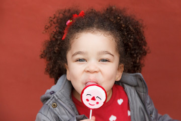 portrait of an ethnic little girl holding a lollipop
