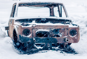 One old abandoned rusty and broken car in snow in Russian winter forest under a tree. Toned in color.