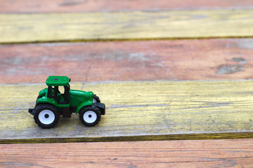 toy green tractor on a yellow-red wooden table