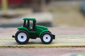 toy green tractor on a yellow-red wooden table