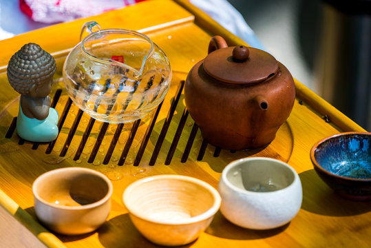On the table on a wooden tray a teapot with tea, teapot, cups. Man, hands pouring tea