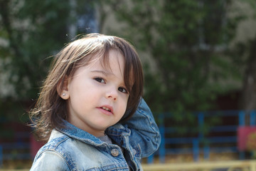 closeup portrait of little cute emotional girl with pigtails in a denim jacket