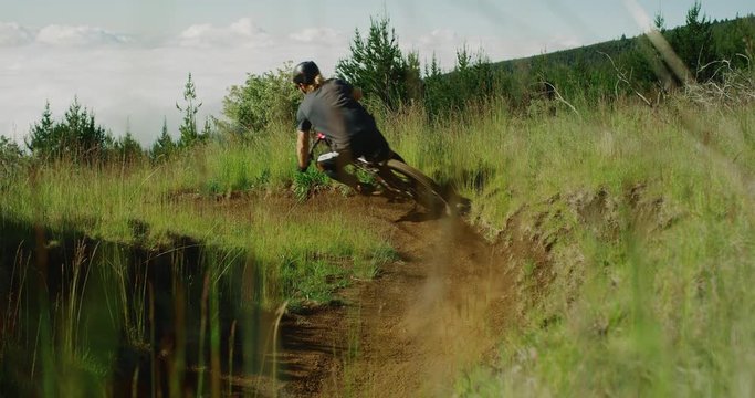 Summer mountain biking adventures, active adventurous man riding his mountain bike around a berm turn in slow motion