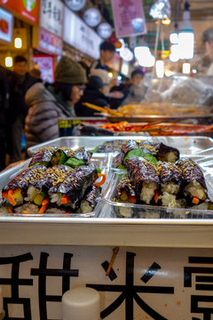Korean-style gimbap (also known as 'kimbap') sushi rolls for sale among diners at lunch time in the famous, crowded Gwangjang Market in Seoul